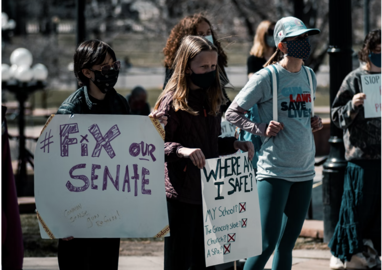 Students holding posters "Fix our Senate" and "Where Am I Safe?"