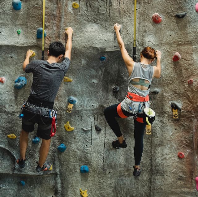Man and woman climbing rock wall side by side