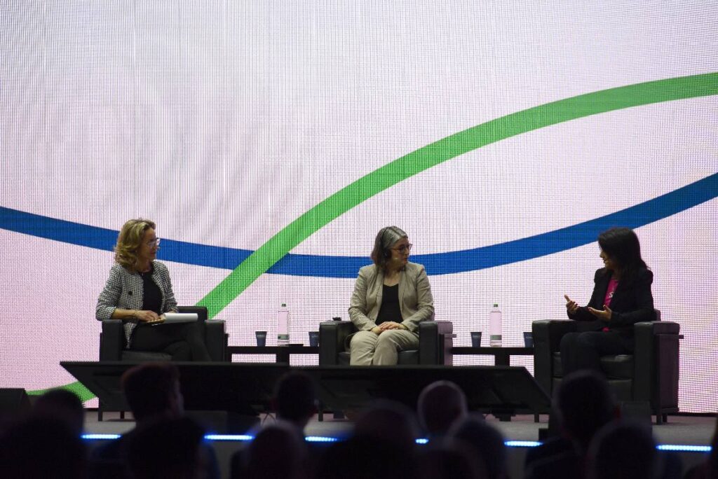 Panelists Maria Pia Quaglia, Michele Wucker, and Claudia Collu seated in 3 chairs on a stage.