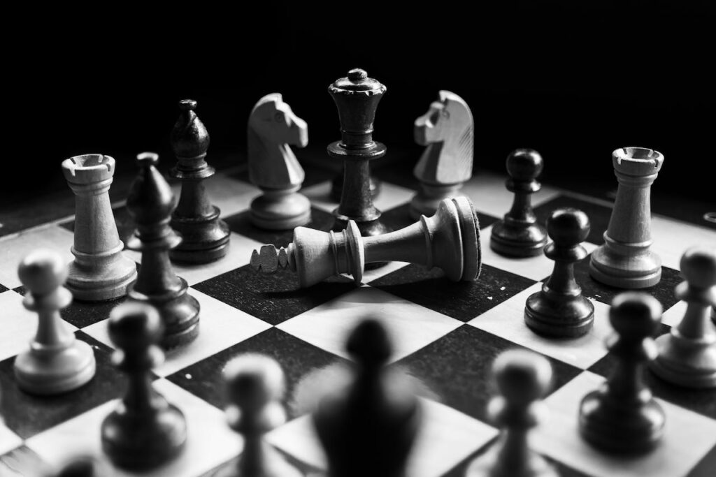 Don’t Let Cognitive Biases Topple Your Strategic Plan chessboard with various pieces and fallen King